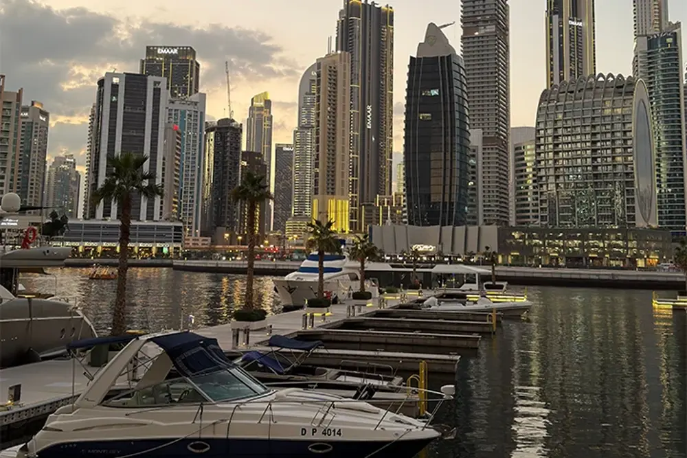 Dubai Marina med skyskrapor, palmer och båtar i kvällsljus
